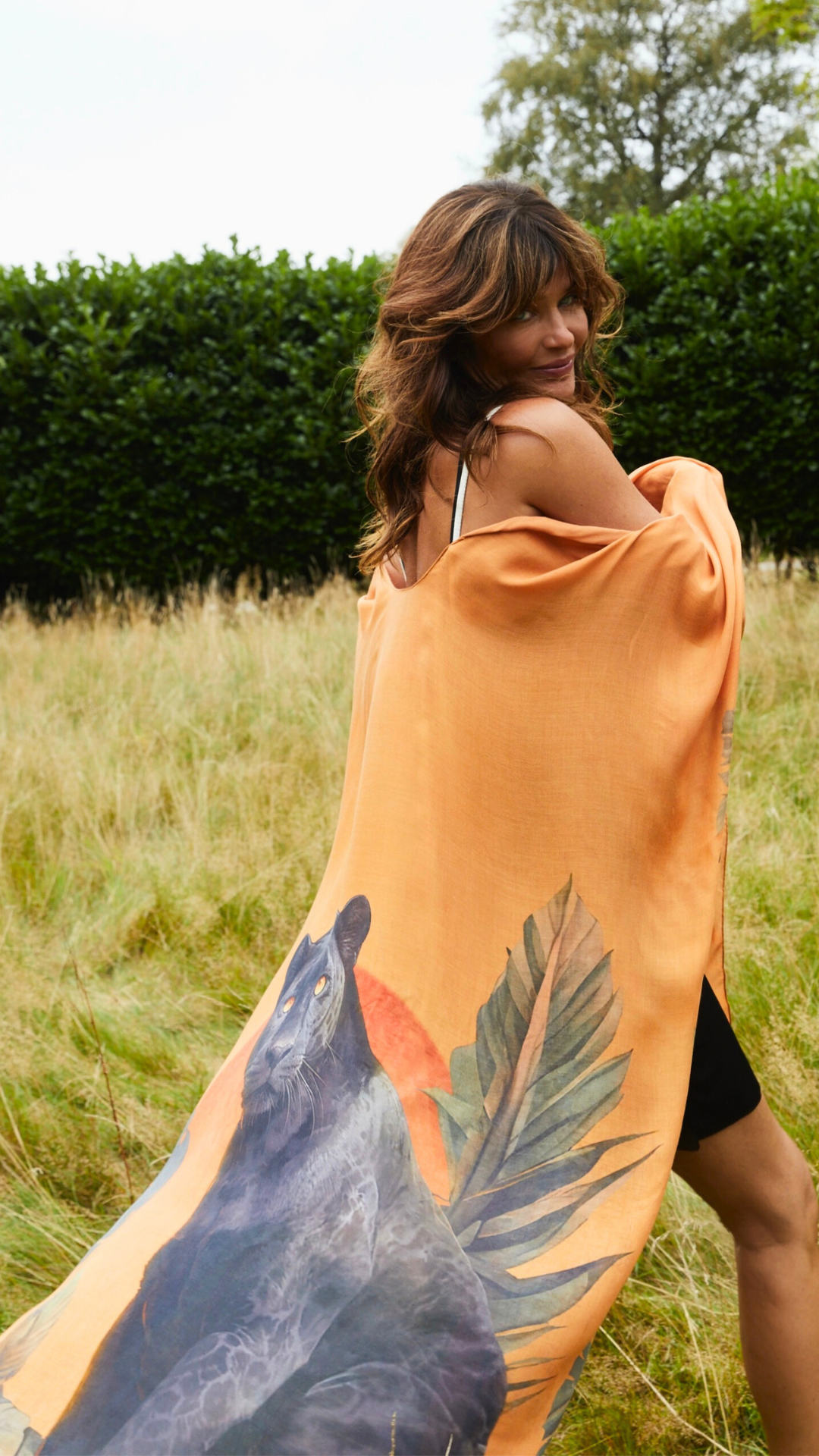 Helena Christensen wearing the orange panther-print resort wear design